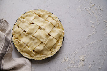 Uncooked apple pie with a wide lattice on top. Concrete background, preparation process.