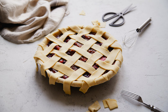 Uncooked berry pie with a lattice decoration on top. Concrete background, cooking process.