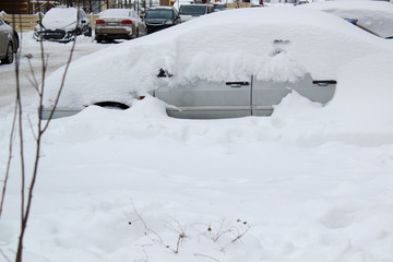 Parked car under snow cover. Winter parking background