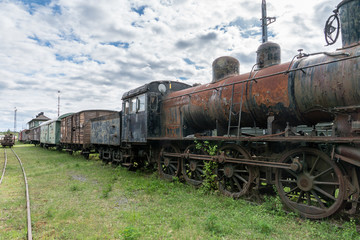 Fototapeta na wymiar Old abandoned steam locomotive with train set