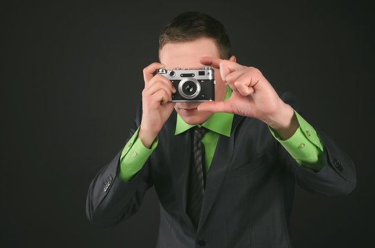 Spy agent with photo camera is photographing a compromising evidence isolated on the black background.