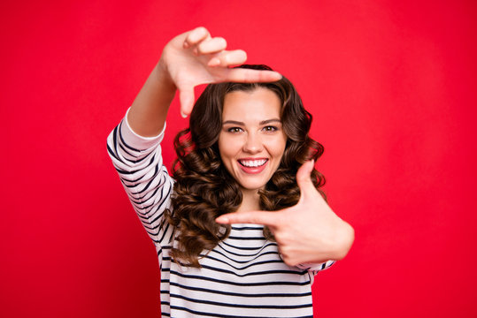 Close up portrait of glad attractive young she her woman with beaming smile making frame with thumbs and forefingers looking through camera isolated on red vivid bright background