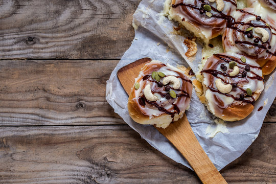 sinabon with cream cheese and cream, chocolate and cashew nuts on wooden background