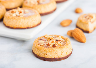 Homemade biscuit cookies with almond nuts and peanut butter on marble board on white kitchen table background.