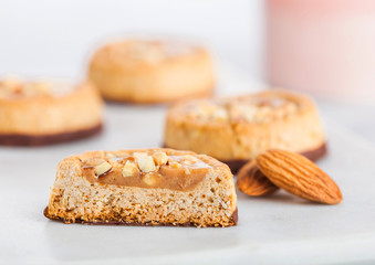 Homemade biscuit cookies with almond nuts and peanut butter on marble coasters on white kitchen table background.