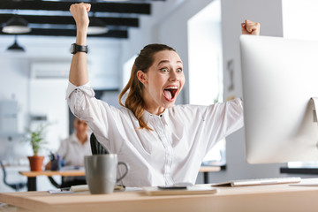 Happy young businesswoman sitting at her workplace