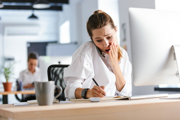 Obraz premium Shocked young businesswoman sitting at her workplace