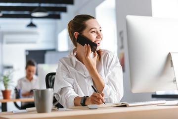 Cheerful young businesswoman sitting at her workplace