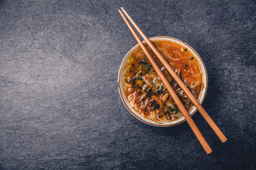 Asian noodles with vegetables and sticks on a dark background, top view with copy space
