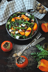 Colorful healthy persimmon salad. Vegetarian salad with persimmon, arugula and white cheese.Colorful, healthy foods in flatlay.