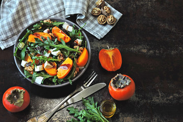 Colorful healthy persimmon salad. Vegetarian salad with persimmon, arugula and white cheese.Colorful, healthy foods in flatlay.