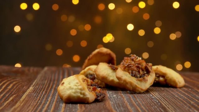 Italian Fig Cookies Cucidati falls on a wooden surface against the background of Christmas light strings, buccellati, traditional sicilian pastry
