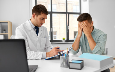 medicine, healthcare and people concept - doctor with clipboard talking to devastated male patient...