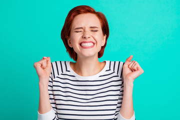 Close-up portrait of nice crazy childish attractive lovely pretty excited red-haired lady in striped pullover holding fists isolated over bright vivid shine green turquoise background