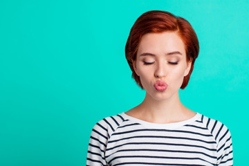 Fototapeta premium Close-up portrait of her she nice lovely sweet attractive adorable red-haired lady in striped pullover sending air kiss closed eyes isolated over bright vivid shine green turquoise background