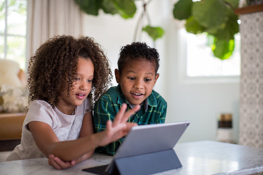 African American brother and sister playing together on digital tablet