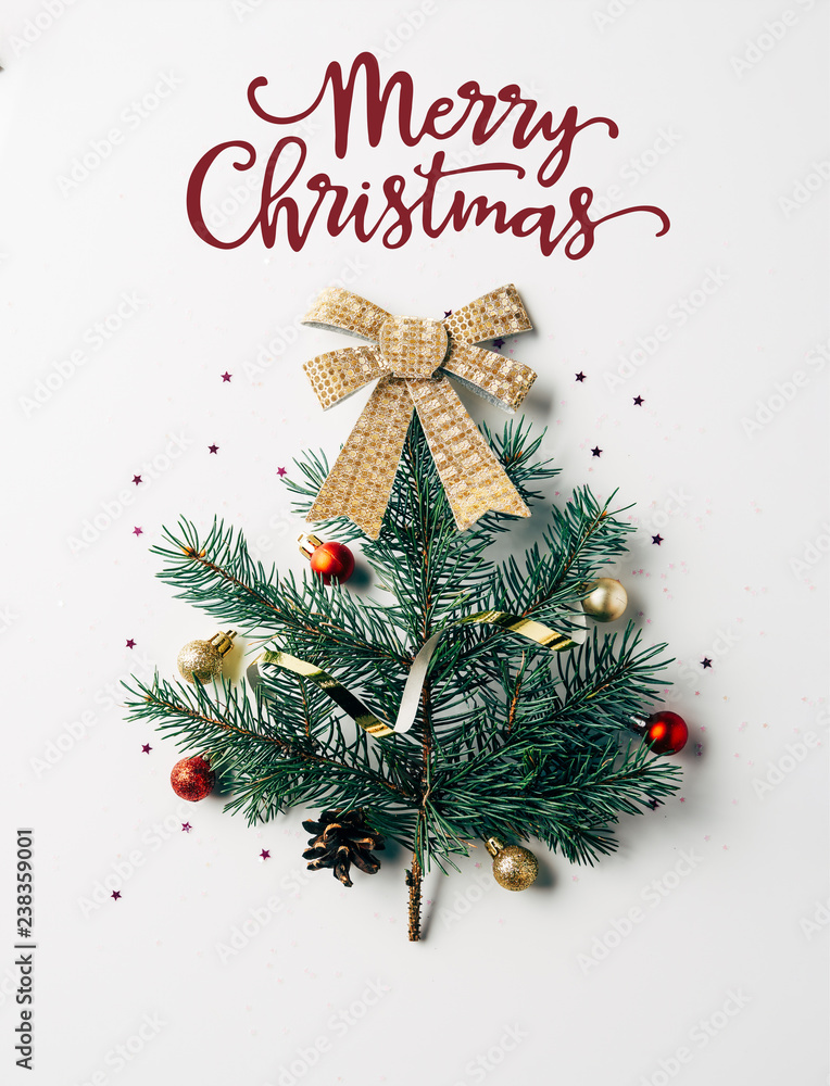 Wall mural top view of green pine branch decorated as festive christmas tree with bow on white background with 