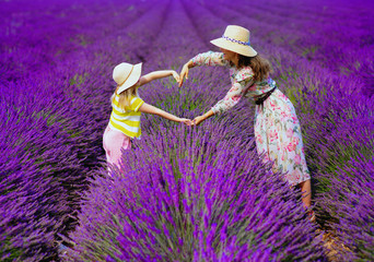 mother and child against lavender field making heart with hands