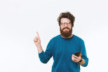 Naklejka premium Portrait of man pointing away at copyspace and holding smartphone