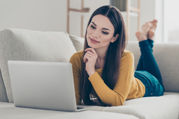 Close-up portrait of nice lovely cute sweet tender attractive charming cheerful straight-haired girl lying on divan barefoot preparing homework task freelance in light interior room