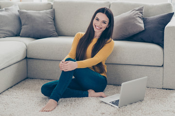 Portrait of nice lovely sweet attractive adorable charming cheerful positive straight-haired girl sitting barefoot on carpet preparing homework task freelance in light interior room