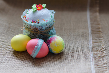 Handmade colorful Easter eggs, Easter cake on the background of brown coarse cloth