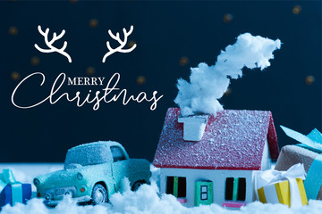 close-up shot of miniature car with christmas gifts and house covered with snow at night, with...