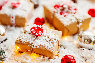 Christmas and New Year background with presents, ribbons, balls and different decorations on snow. Present packed in craft paper with heart, symbol of love.