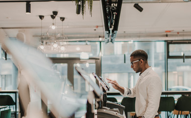 Stylish black man using cash register