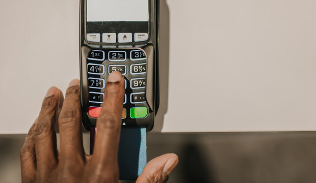 Crop black hand inserting password on payment terminal