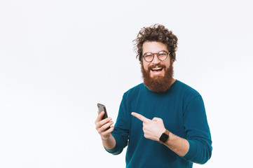 Cheerful handsome bearded man poinitng at smart phone