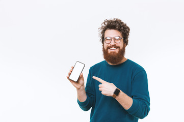 Portrait of happy bearded man pointing at blank screen on smartphone