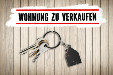 Schlüssel mit Schlüsselanhänger in Hausform auf Holzuntergrund un der Nachricht 