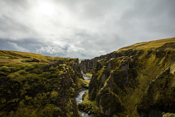 Deep canyon, steep cliffs overgrown with green moss, surrounded by a very fast river with cold water. Canyon of Icelandic tales - Fjardrarglufur