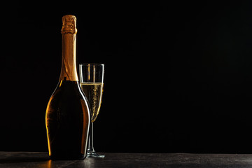 bottle of champagne and glasses over dark background