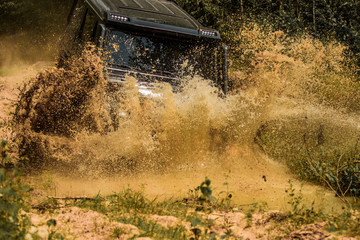 Off-road vehicle goes on mountain way. Offroad vehicle coming out of a mud hole hazard. Expedition offroader. Safari suv. 4x4 travel trekking. Road adventure. Adventure travel. © Volodymyr