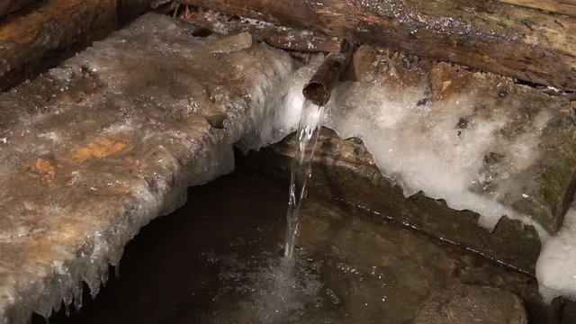 The source of artesian water flows in the winter Christmas. Fun water rushing.