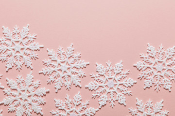 White glitter snowflake composition on a pastel pink background