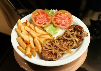 Plato combinado con dos hamburguesas con cebolla frita,  ensalada y patatas fritas.