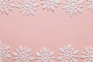 White glitter snowflake composition on a pastel pink background