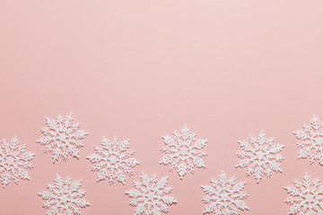 White glitter snowflake composition on a pastel pink background