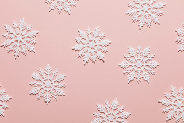 White glitter snowflake composition on a pastel pink background