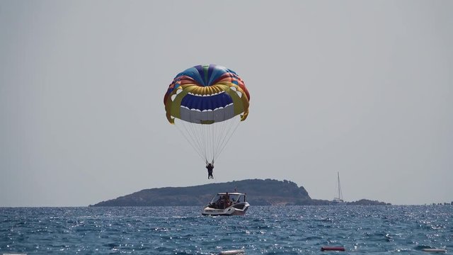 Parasailing behind a boat people flies over the sea on a parachute