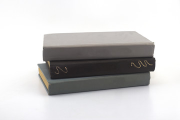 two gray and one brown old books on a white background close-up