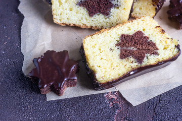 Vanilla pound cake with chocolate glaze served with chocolate biscuit stars on brown paper. Brown stone table. Copy space.