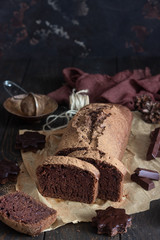 Delicious dark chocolate cake on paper on dark wooden background. Selective focus. Copy space. Christmas or New Year chocolate cake.
