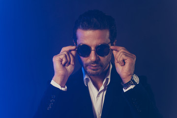Obraz premium Close-up portrait of nice attractive handsome serious confident content classy elegant man wearing black jacket touching round glasses isolated over dark blue fume smoke background