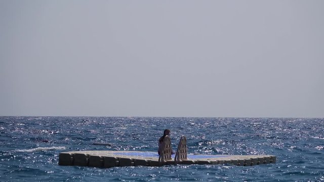 Girl sits on a raft in the middle of the open sea