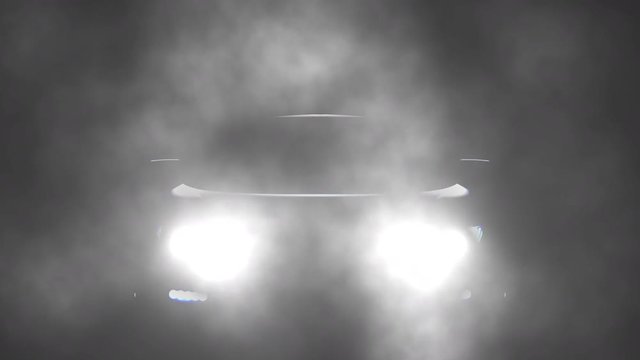 Car headlights on a dark foggy night.