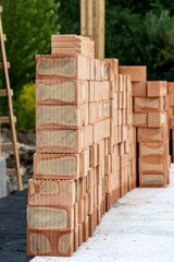Construction of new house. Vertical photo red rectangular brick lay in stack on floor foundation
